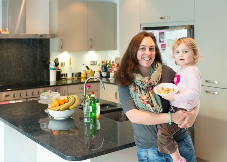Kate smiling holding her baby in her new kitchen