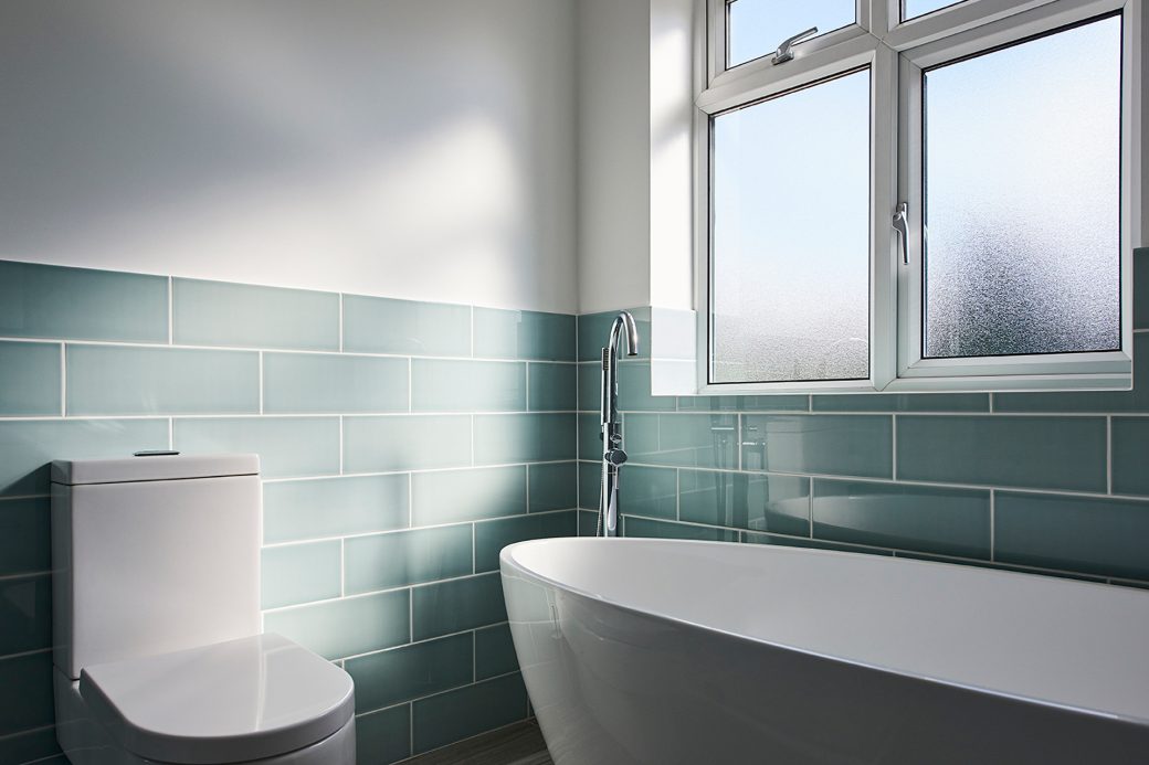 Azure blue tiles next to white free standing bath