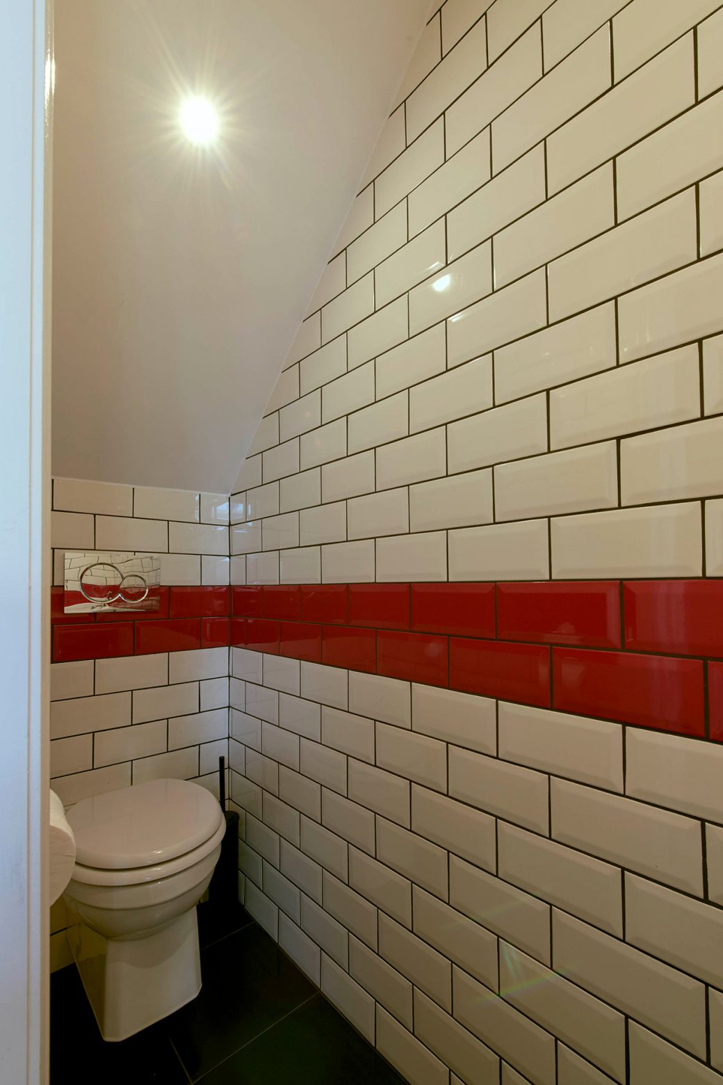 Bathroom with white subway tiles with a contrasting red stripe of tiles